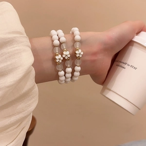 Close-up of a three-piece acrylic beaded bracelet set with elegant white flower pendants