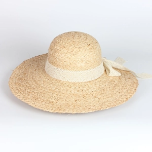 Close-up of wide brim raffia sun hat featuring woven texture and white lace ribbon bow