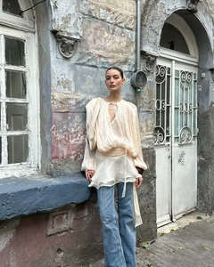 Detail view of beige chiffon puff sleeve top with v-neck drawstring and tiered ruffle hem