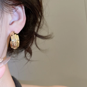 Detailed view of chunky golden twisted wave hoop earrings with textured metallic surface