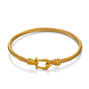 Gold plated stainless steel cable bracelet featuring a horseshoe buckle clasp