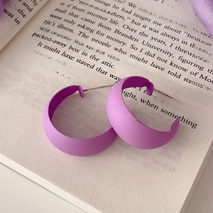 Macro detail of lavender purple matte hoop earrings on an open book page