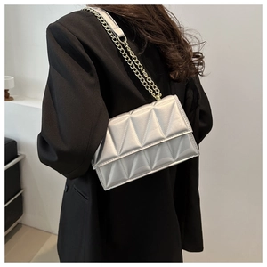 Detail of silver quilted crossbody bag with metallic chain strap and geometric stitching