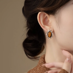 Close-up of vintage oval earring with brown tiger eye stone and small pearl borders