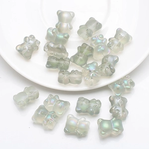 Macro view of pearlescent grey 3D bear charms scattered on a white ceramic plate