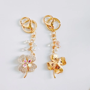 Detail of golden four-leaf clover keychain with sparkling crystals and transparent beads