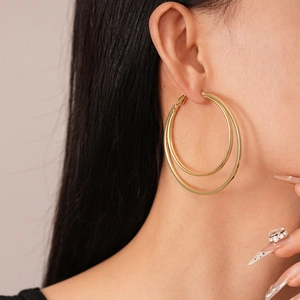 Close-up of a model wearing gold double-layer geometric hoop earrings in a minimalist style