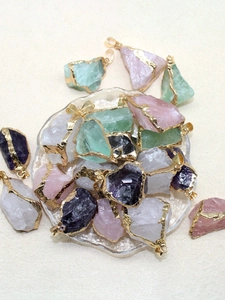 Détail de pendentifs en pierres précieuses naturelles avec bords dorés et cristaux