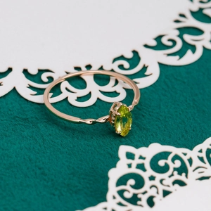 Detail of rose gold rope band ring with marquise cut olive green gemstone on velvet