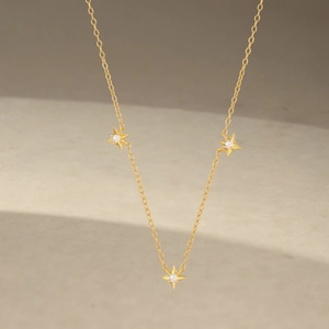 Close-up of gold star pendants with iridescent opal stones on a delicate silver chain