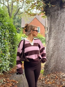 Outdoor shot of a striped polo knit sweater with a white collar and long sleeves
