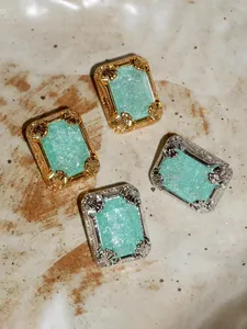 Macro view of vintage 18K gold and silver mint blue gemstone earrings with shell textures