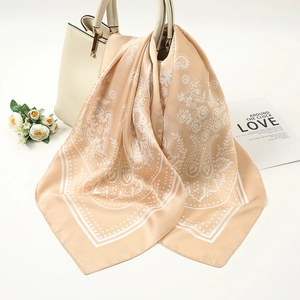 Detail of champagne gold paisley silk scarf draped on a bag with floral decor