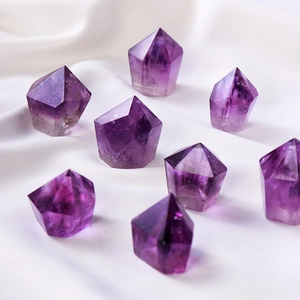 Polished natural purple amethyst crystal hexagonal prisms on white fabric background
