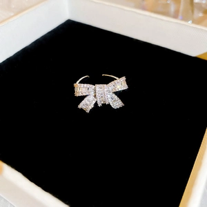 Close-up of silver bow ring with white cubic zirconia inlay on black velvet background