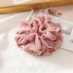 Detailed close-up of pink scrunchie with pleated fabric and delicate beaded edge
