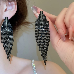 Gros plan de boucles d'oreilles pompons en strass noirs avec design trapèze géométrique
