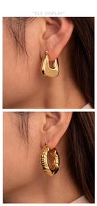 Detail of gold U-shaped and twisted rope textured hoop earrings on professional model