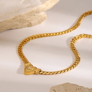 Detailed macro of gold Cuban chain necklace with sparkling heart-shaped diamond clasp