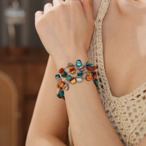 Macro detail of multi-layered beaded bracelet with colorful irregular shells on wrist