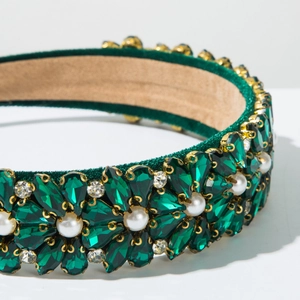 Detailed close-up of velvet headband with emerald crystals and pearl flower patterns