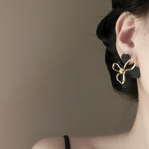 Detail of elegant double-layer floral earrings with matte black petals and gold outlines