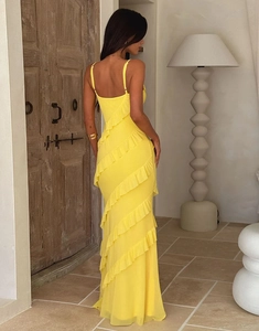 Detailed back view of a yellow backless maxi dress with cascading ruffles in a retro room