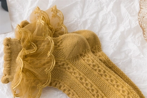 Detailed macro view of yellow cotton knit socks with delicate lace ruffles and floral texture