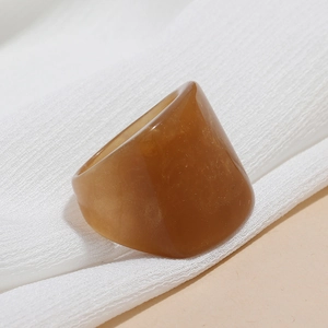 Close-up of translucent amber resin ring texture with warm tones on soft fabric background