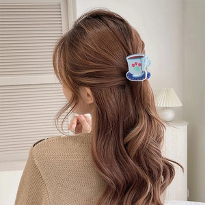 Detail of coffee cup shaped acrylic hair claw clip with floral pattern on long wavy hair