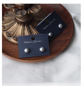 Detailed view of silver grey freshwater pearl earrings on navy display cards