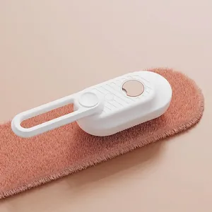 Detail of white steam pet brush showing folding handle on soft pink textured fabric