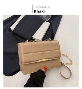 Detail of khaki quilted crossbody bag featuring gold chain strap and metal trim closure