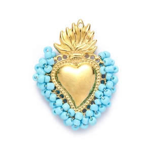 Detailed view of sky blue beaded sacred heart pendant with golden metal and flame top