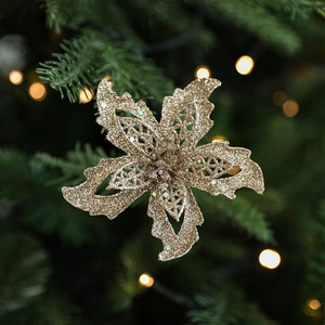 Fleur de Noël dorée scintillante sur sapin avec éclairage bokeh chaleureux et festif