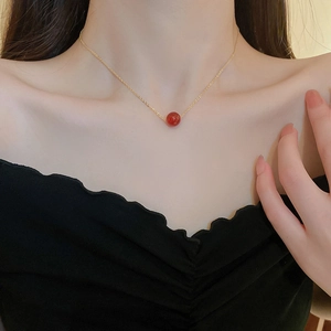 Elegante vergoldete Halskette mit rotem Anhänger an einem Modelhals gezeigt