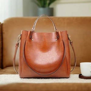 Detailed view of caramel brown oil-wax leather bucket bag on a soft beige carpet