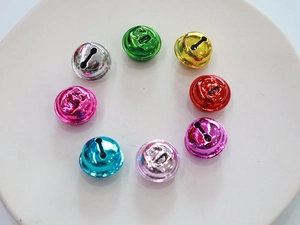 Colorful plated metal bells in various vibrant hues arranged in a circular pattern on white plate