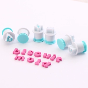 Detail of letter cookie cutters and pink fondant spelling out biscuit mold on white