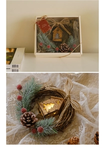 Close-up of Christmas wreath with LED wooden house, pine cones, and red berries in gift box