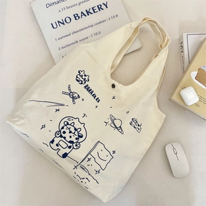 Close-up of cream canvas tote bag with astronaut cow print and secure snap fastener