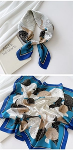 Detail of silk square scarf featuring blue and white camellia floral prints and satin texture