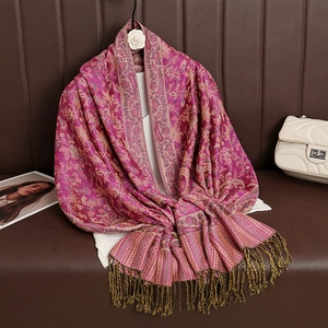 Pink and purple paisley cashmere-style shawl with gold tassels on a wooden hanger