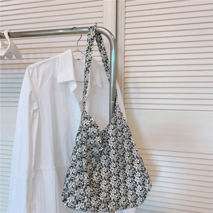 Detailed view of floral canvas tote bag with white flower pattern on black fabric