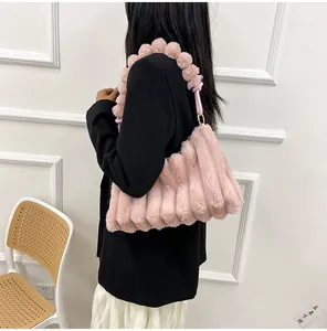 Detail of pink faux fur shoulder bag with textured vertical stripes and plush ball strap