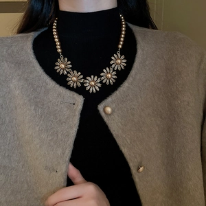 Detail of vintage flower pearl necklace and earrings set worn by a model in soft lighting