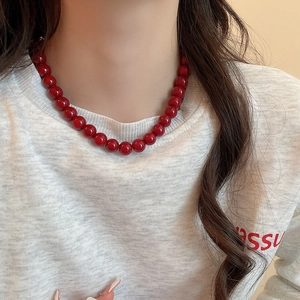 Detailed view of glossy red glass beads on a minimalist necklace worn by a model