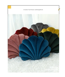 Detail of shell-shaped velvet pillows with scalloped stitching on a plush white rug