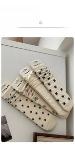 Detail view of four pairs of ballet-style cream socks with bows and floral patterns