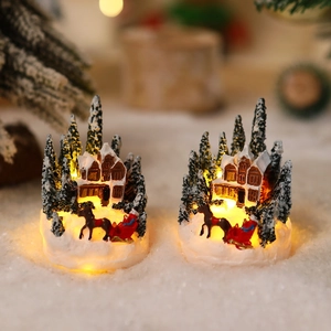Detail of light-up Christmas resin houses with warm LED glow and snow scene decorations